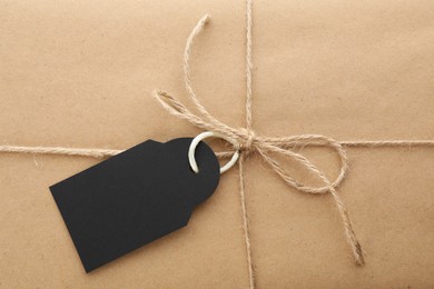 Photo of Parcel wrapped in kraft paper with tag as background, closeup