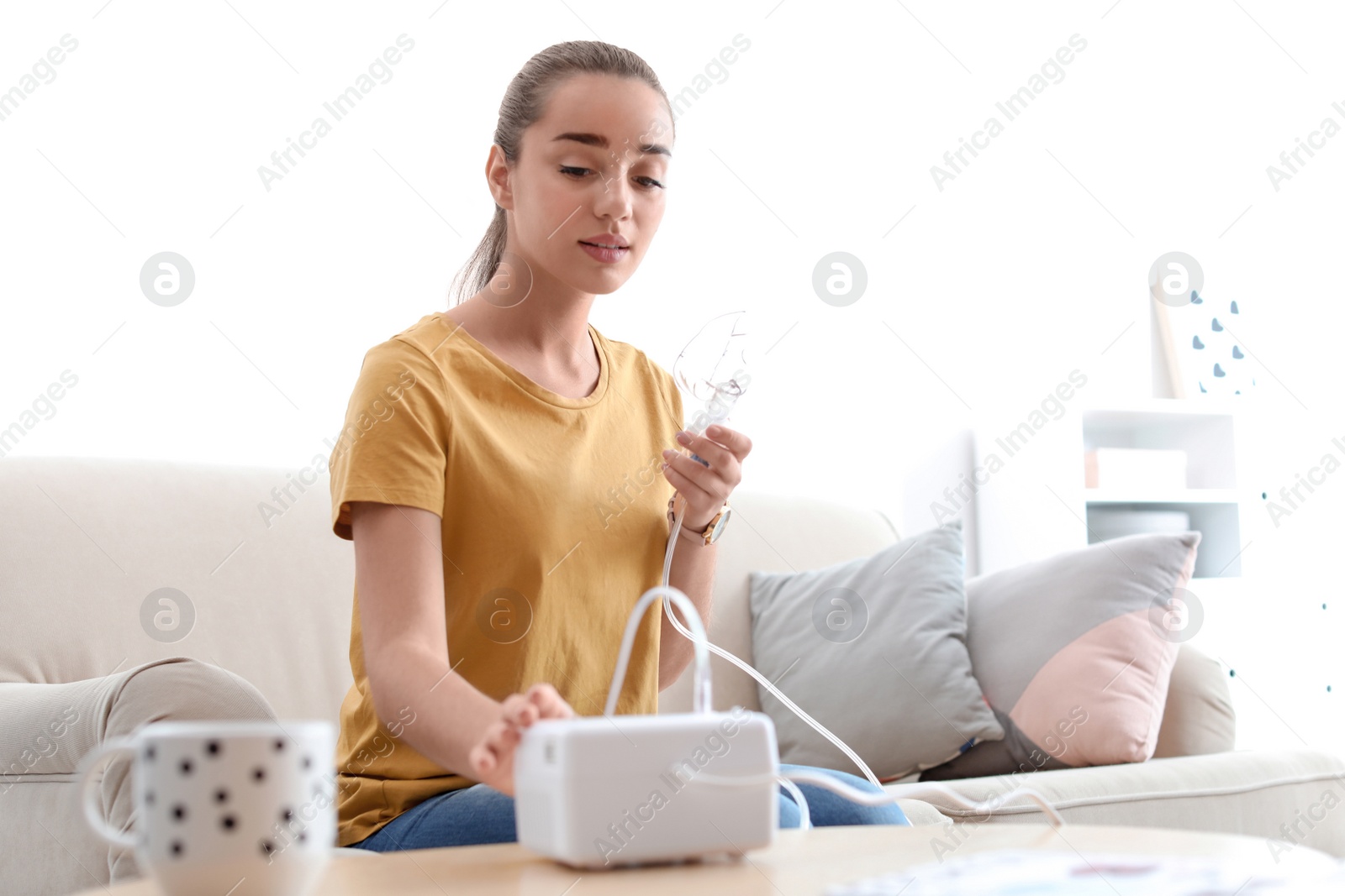 Photo of Young woman using asthma machine at home. Health care