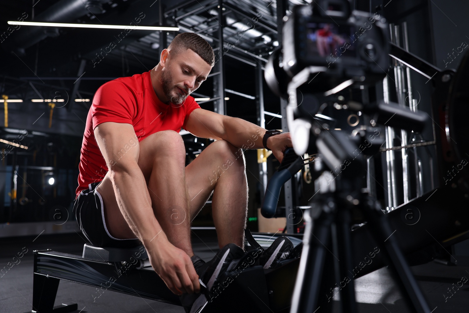 Photo of Man recording workout on camera at gym. Online fitness trainer