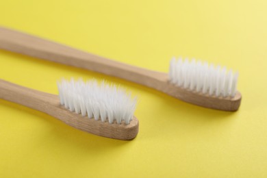 Photo of Two bamboo toothbrushes on yellow background, closeup