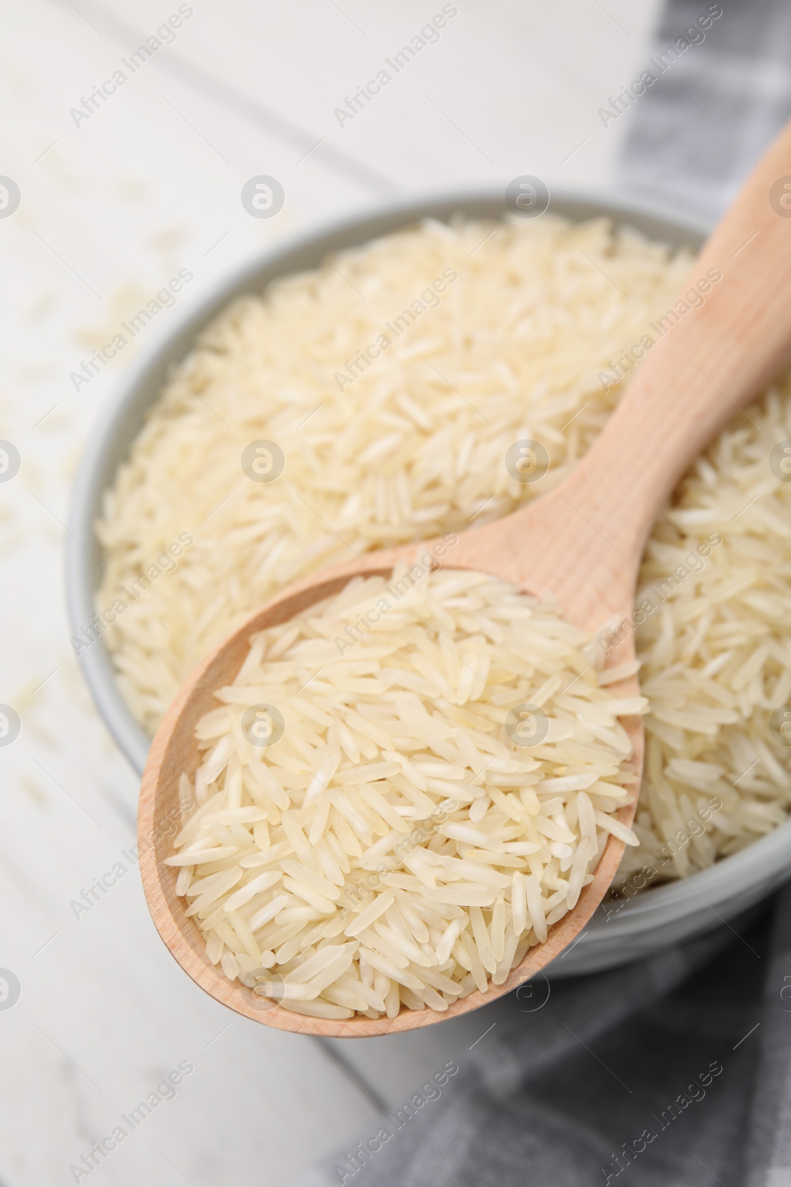 Photo of Wooden spoon and bowl with raw rice on table, above view