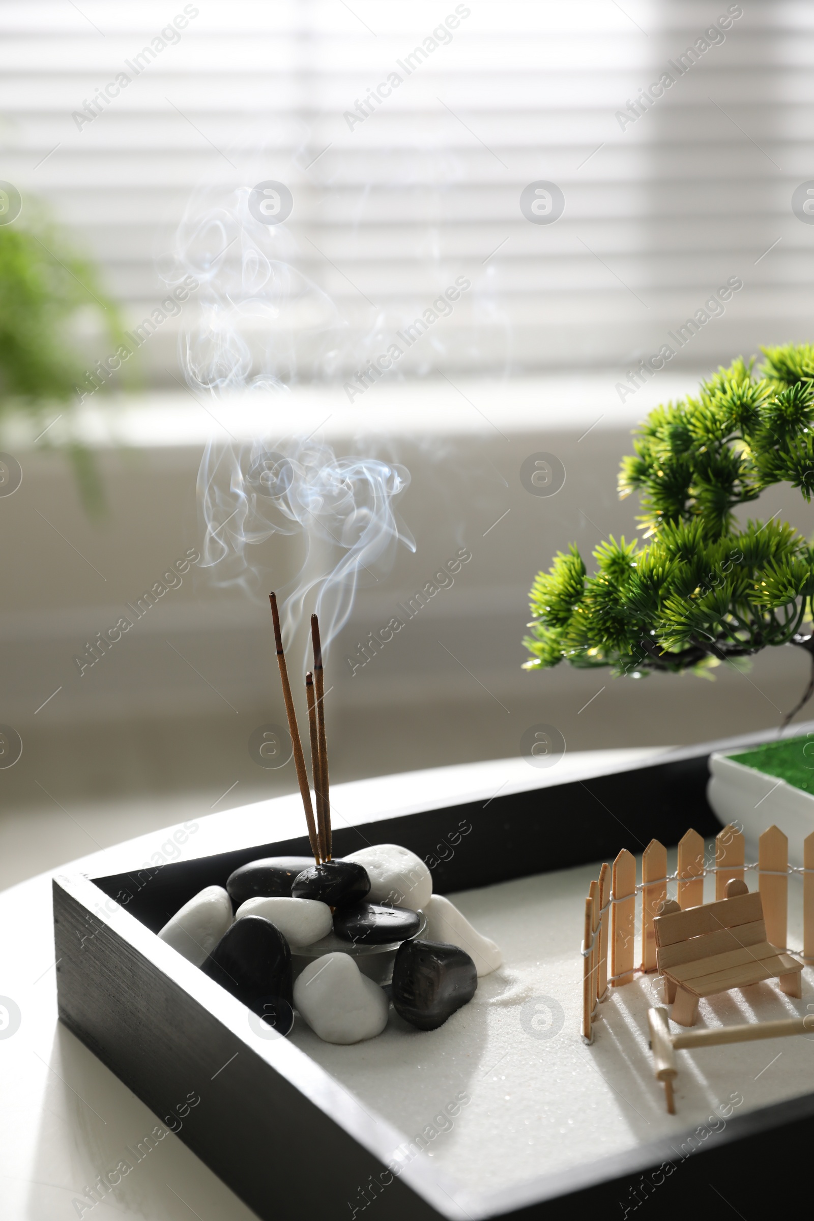 Photo of Beautiful miniature zen garden with incense sticks on table indoors