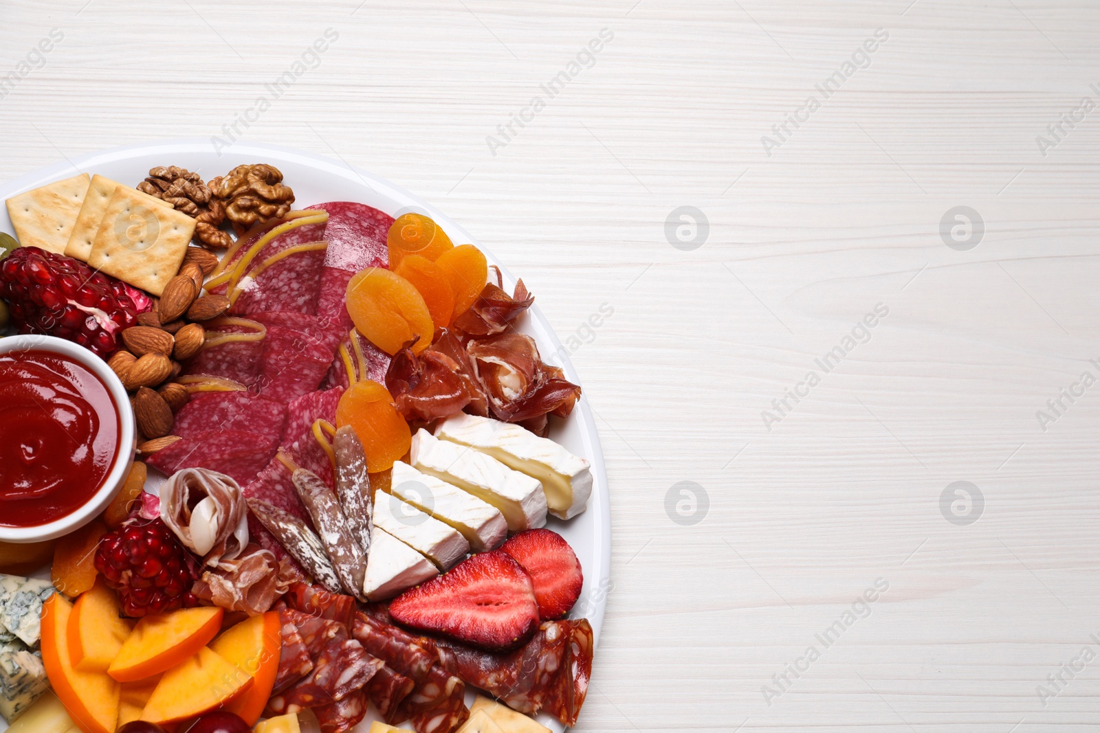 Photo of Plate of different appetizers with sauce on white wooden table, top view. Space for text