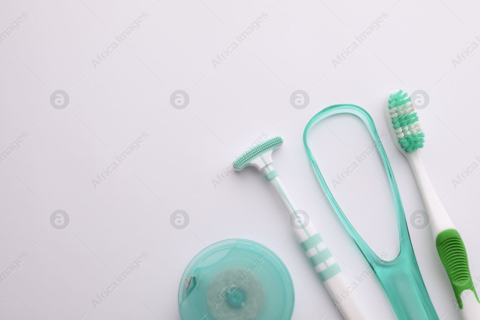 Photo of New tongue cleaners, toothbrush and dental floss on white background, top view