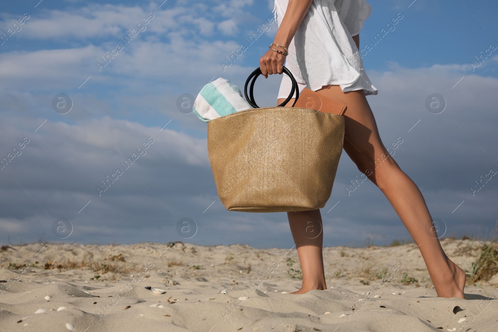 Photo of Woman carrying bag with beach towel on sand, closeup