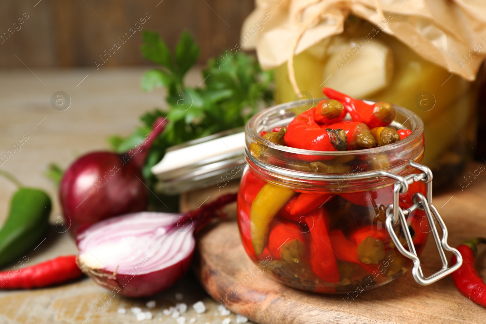 Photo of Glass jar with pickled peppers on wooden table