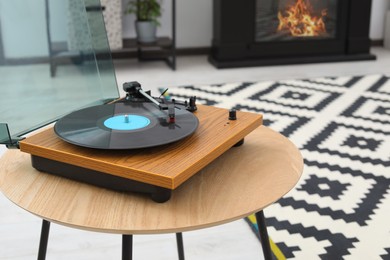 Photo of Vinyl record player on wooden table indoors. Interior element