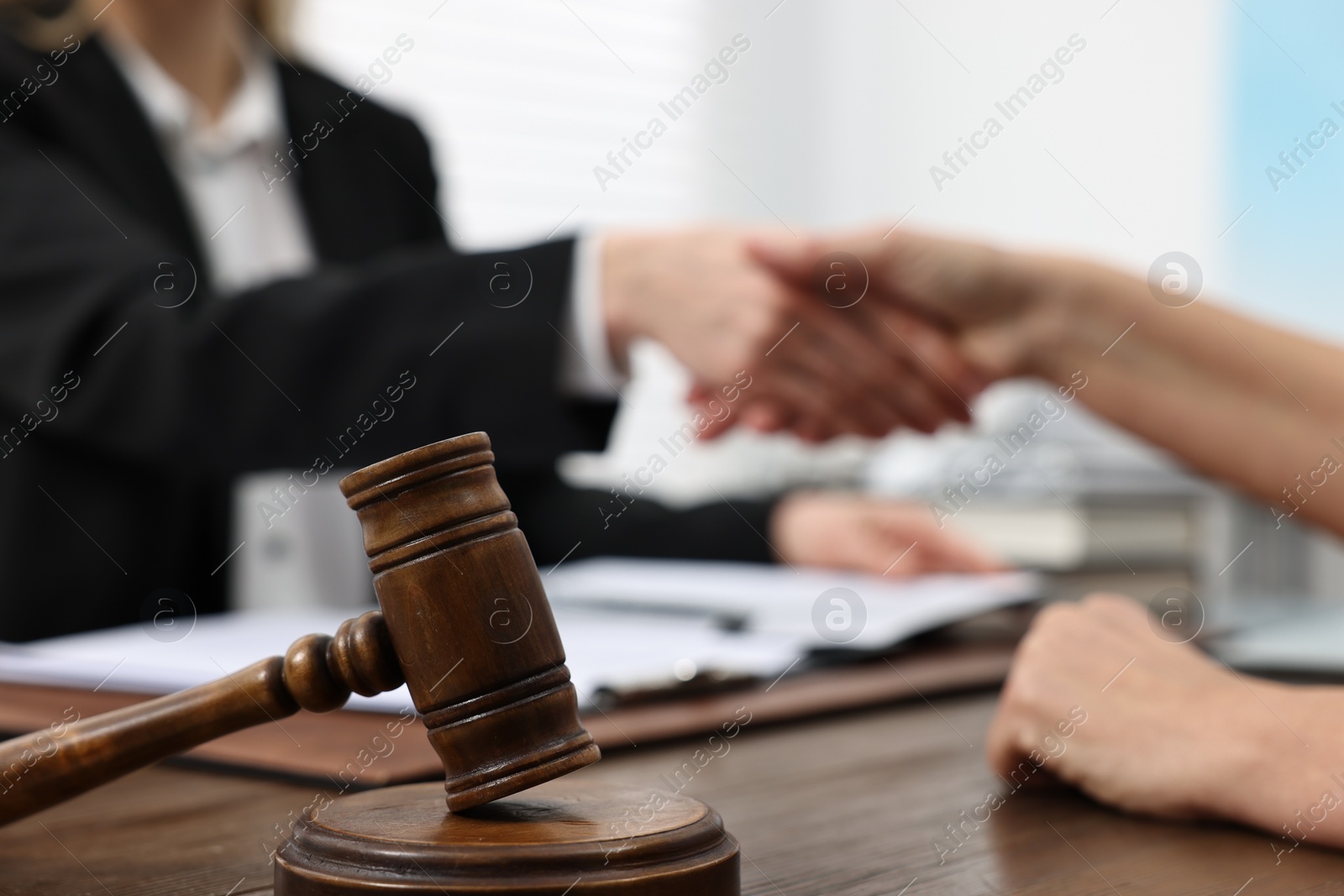 Photo of Lawyer shaking hands with client in office, focus on gavel