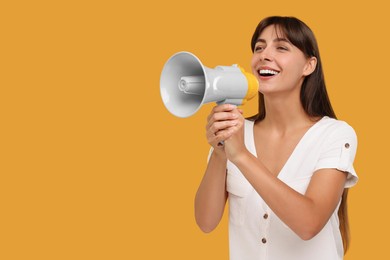 Photo of Special promotion. Woman shouting in megaphone on orange background, space for text