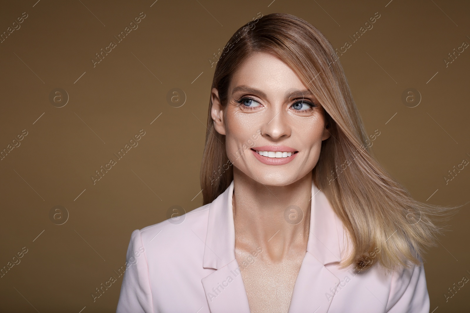 Image of Portrait of stylish attractive woman with blonde hair smiling on pastel brown background, space for text