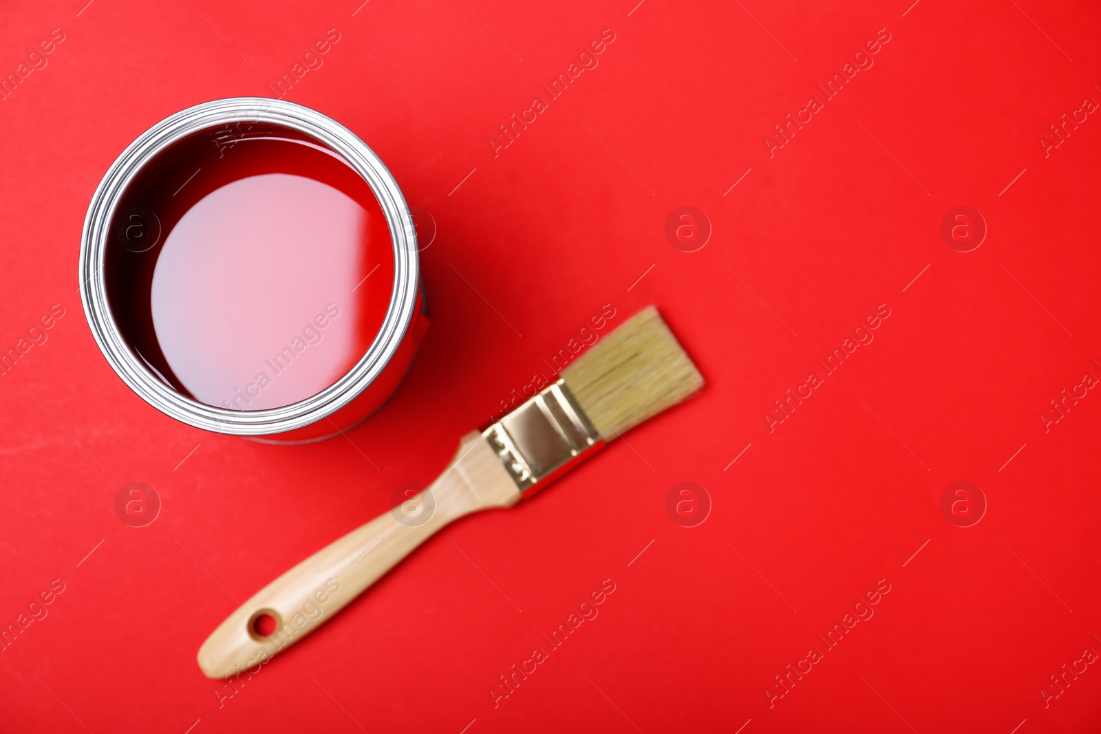Photo of Flat lay composition with paint can and brush on red background. Space for text