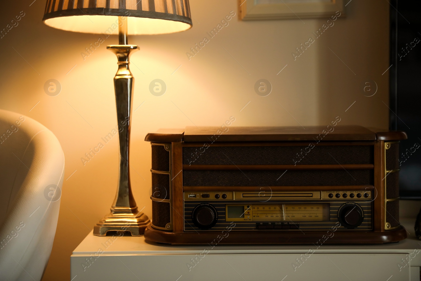 Photo of Vinyl record player and lamp on white table indoors