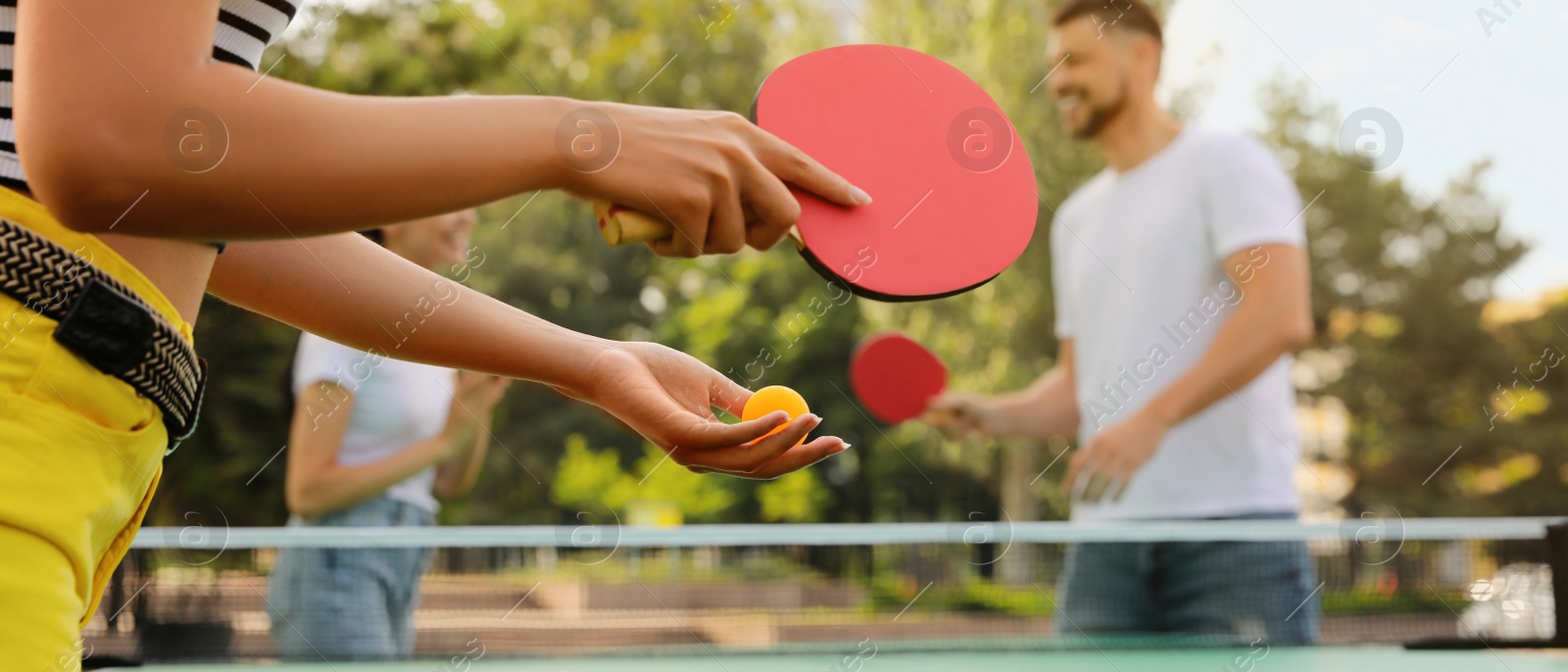 Image of Friends playing ping pong outdoors, focus on hands. Banner design