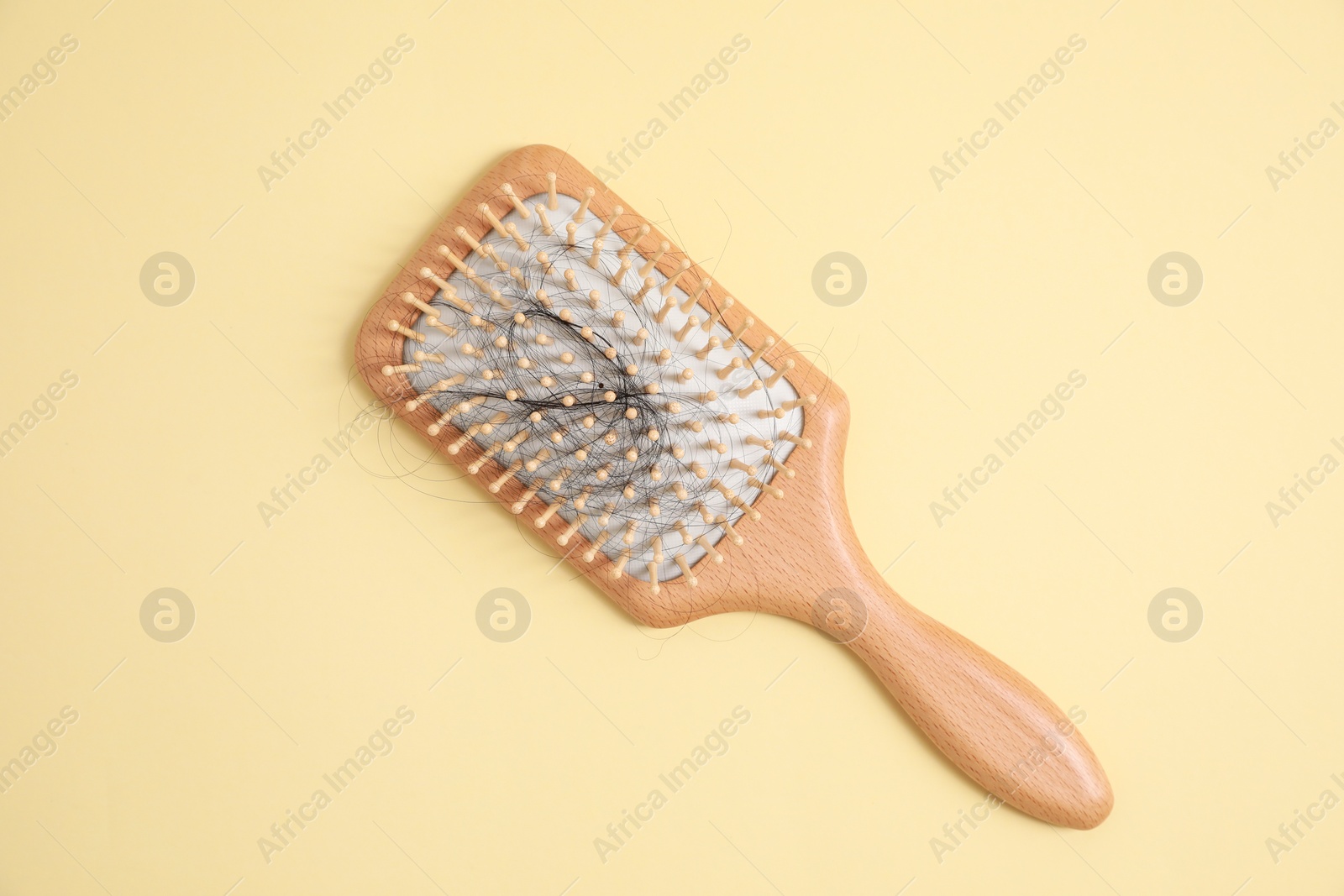 Photo of Wooden brush with lost hair on beige background, top view