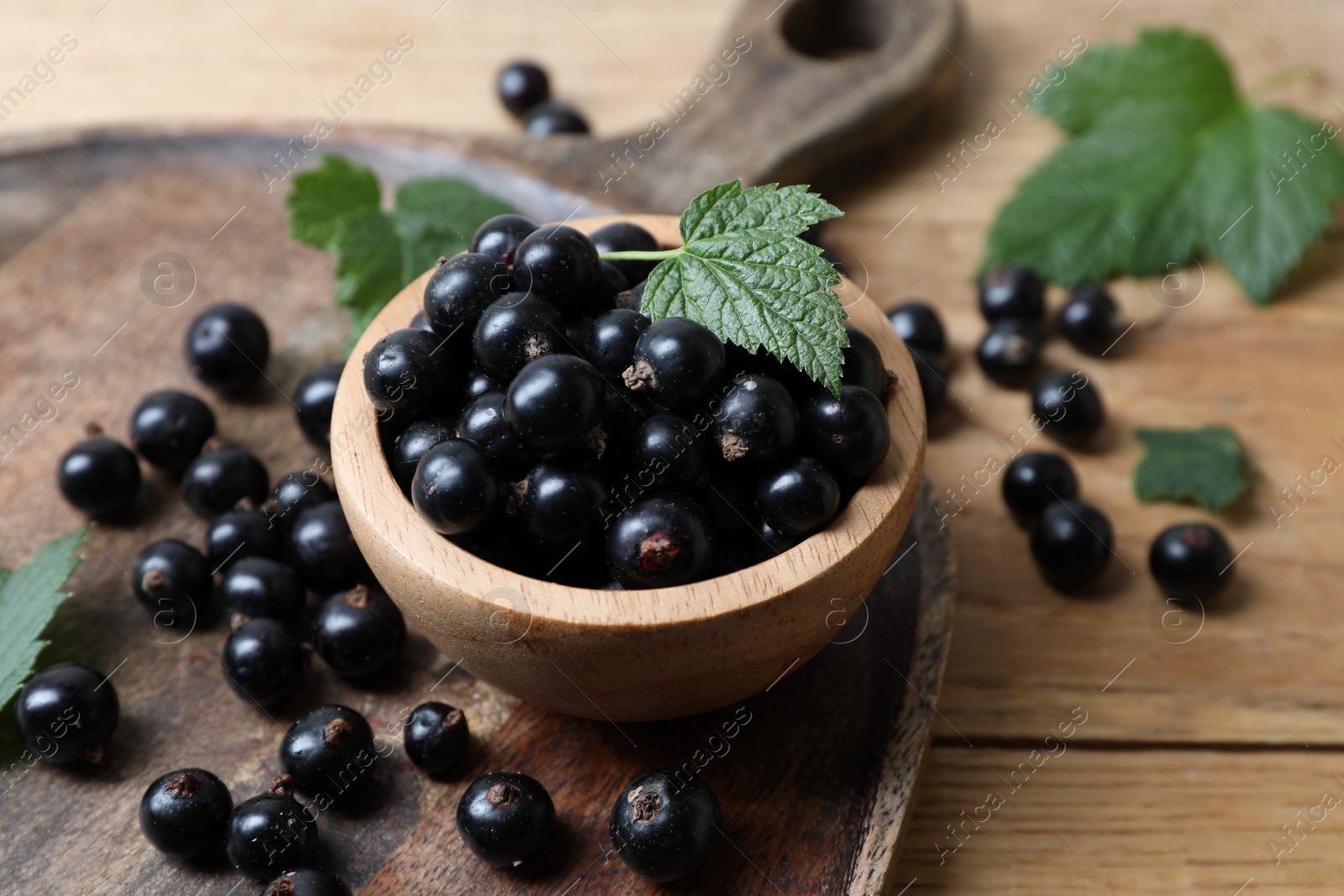 Photo of Ripe blackcurrants and leaves on wooden table, closeup