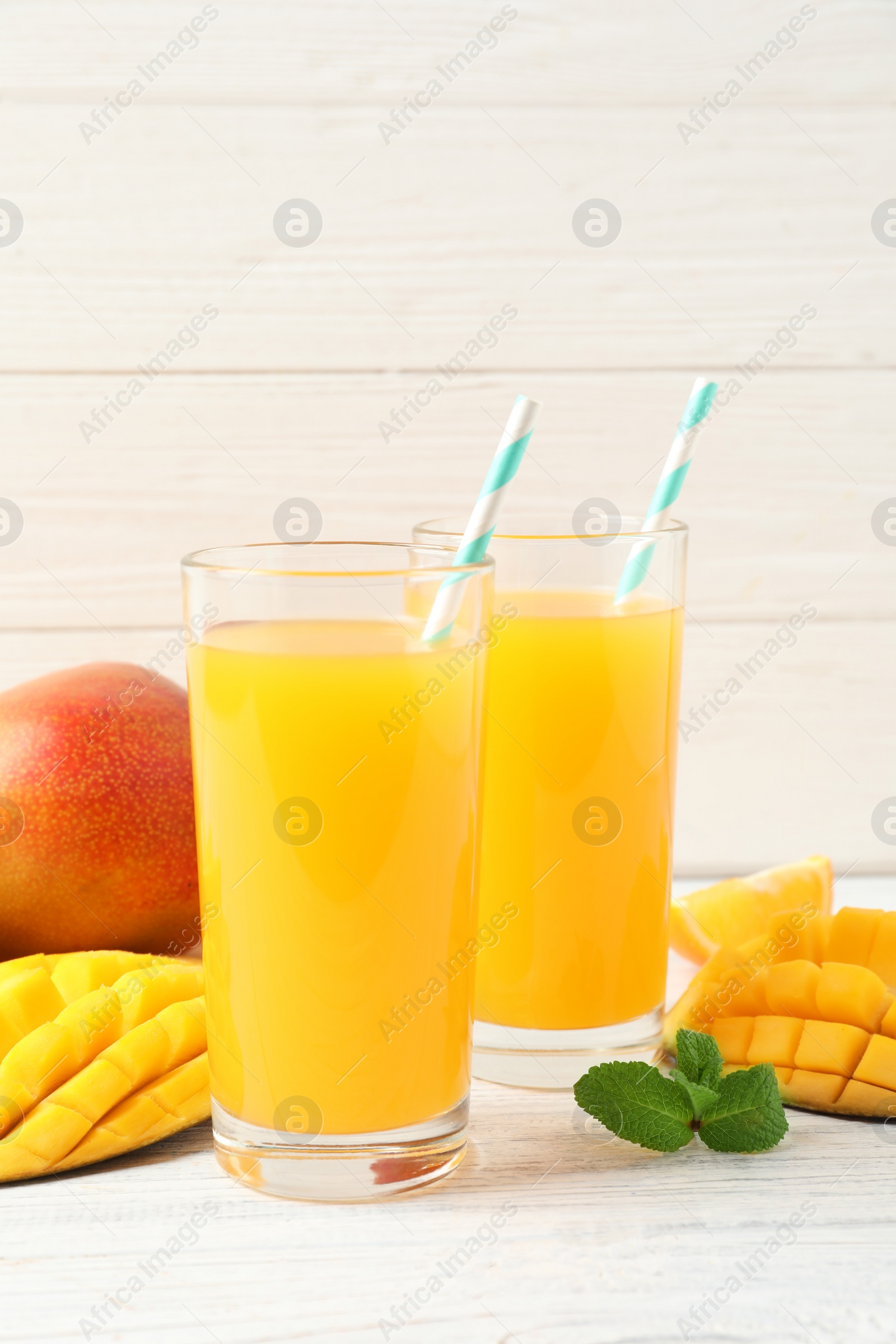 Photo of Tasty mango drink and fresh fruits on wooden table against light background