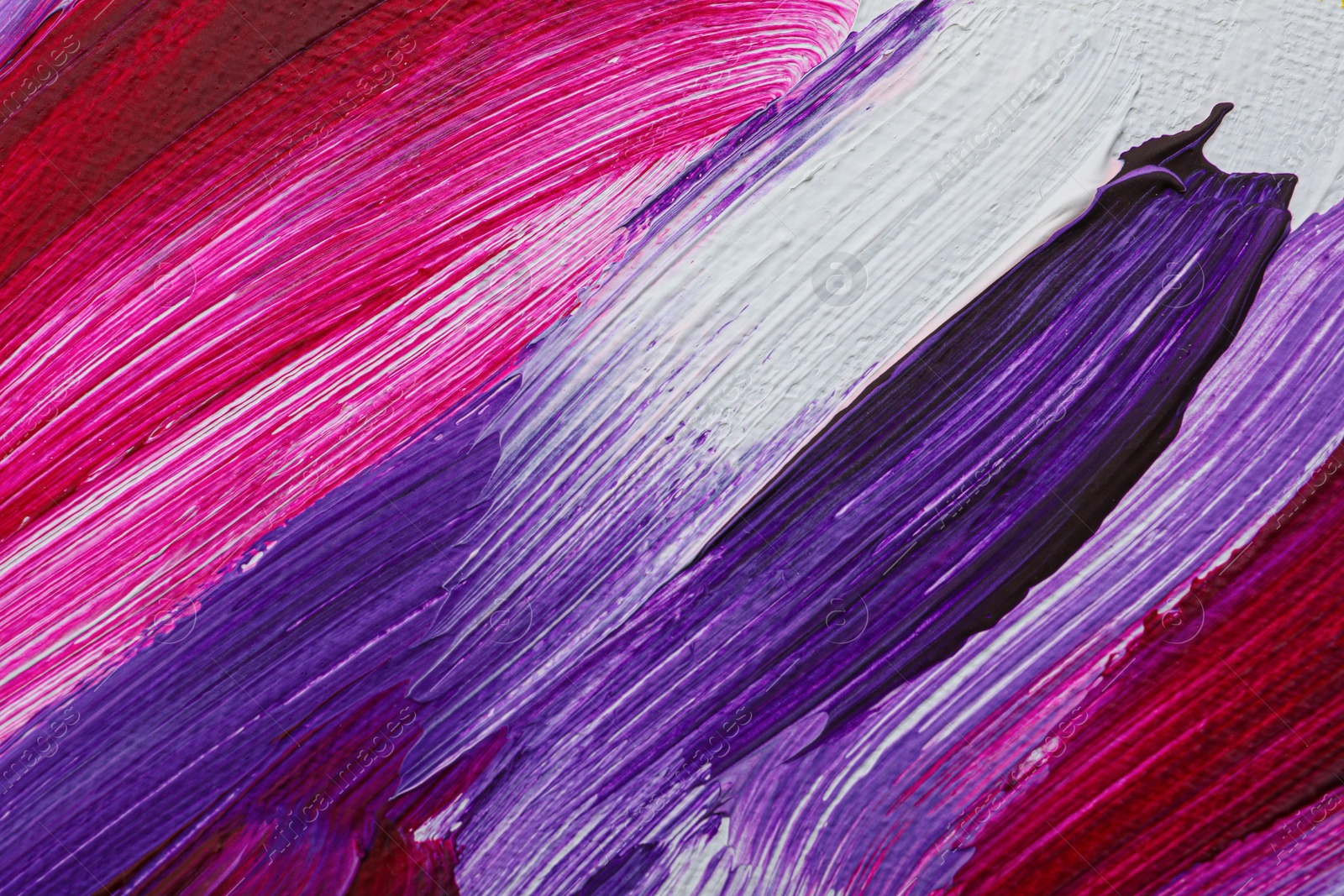 Photo of Strokes of colorful oil paints on white canvas, closeup