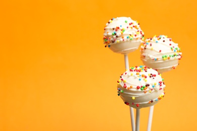 Many bright delicious cake pops on color background. Space for text