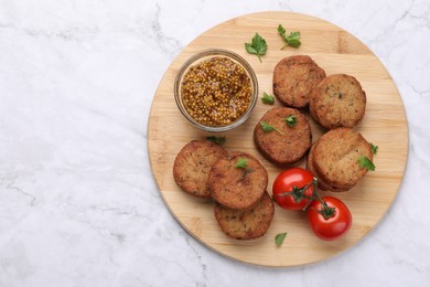 Tasty vegan cutlets, tomatoes and grain mustard on white marble table, top view. Space for text