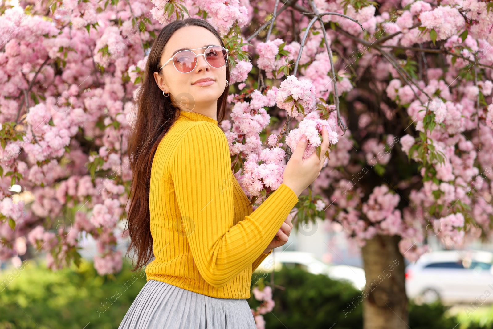 Photo of Beautiful woman in sunglasses near blossoming tree on spring day