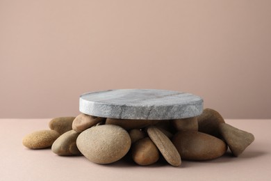 Photo of Presentation for product. Stone podium and pebbles on beige background. Space for text