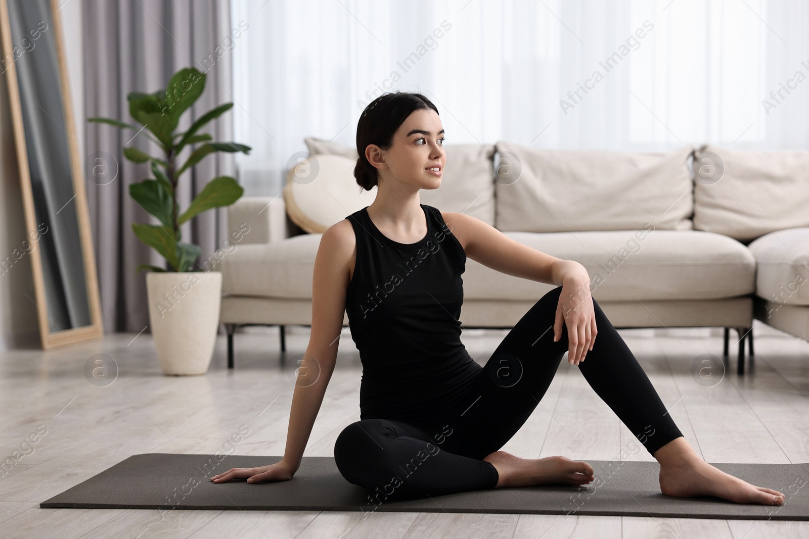 Photo of Beautiful girl sitting on yoga mat at home