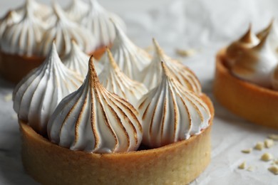 Tartlets with meringue on parchment paper, closeup. Delicious dessert