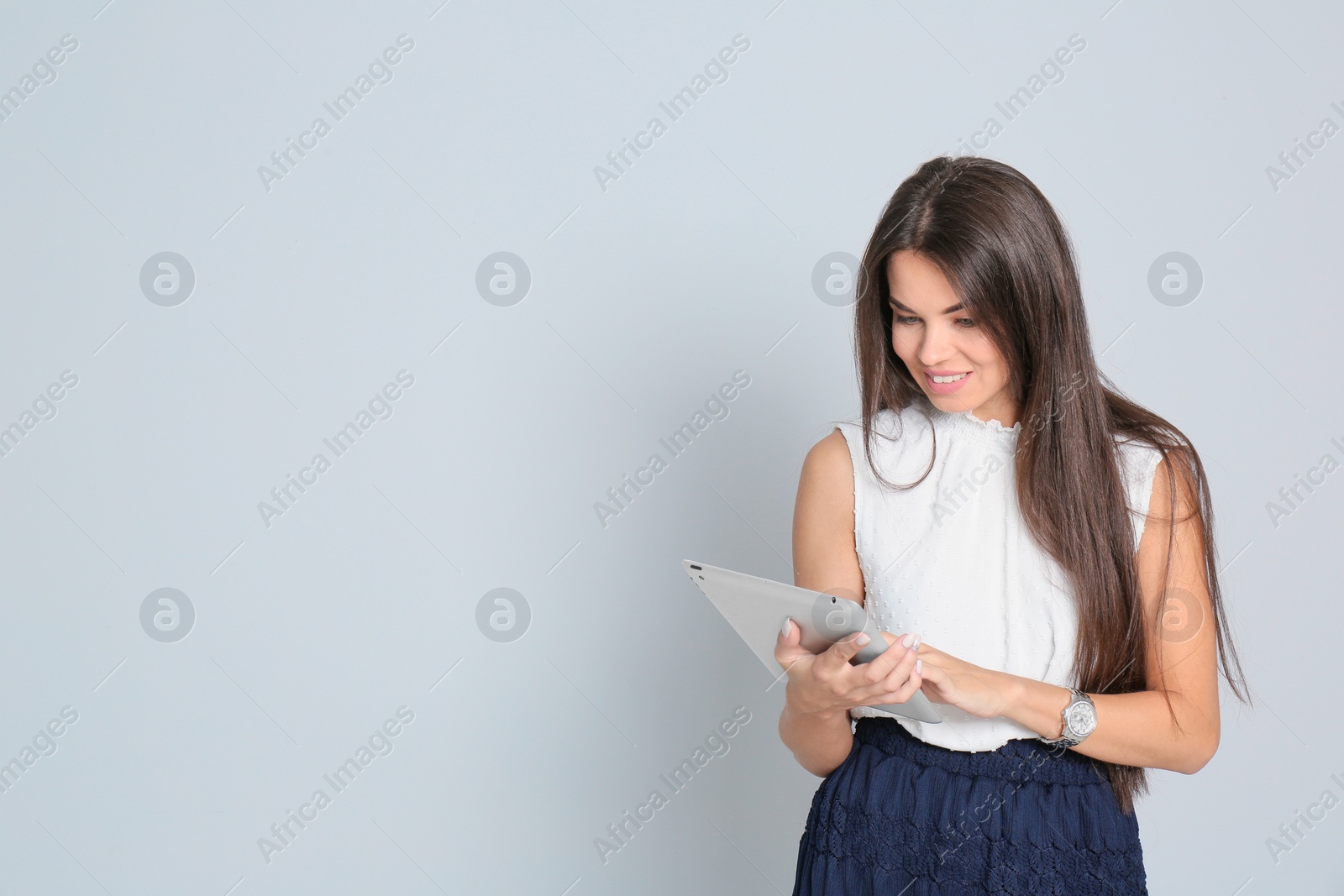 Photo of Beautiful woman with tablet wearing office clothes against gray background. Space for text