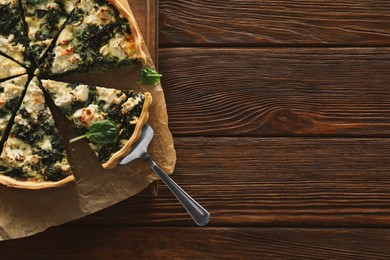 Photo of Delicious homemade spinach quiche on wooden table, top view. Space for text