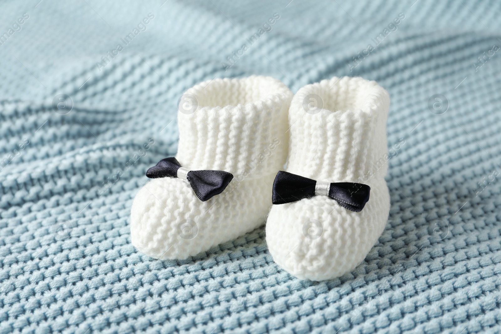 Photo of Handmade baby booties on soft knitted plaid