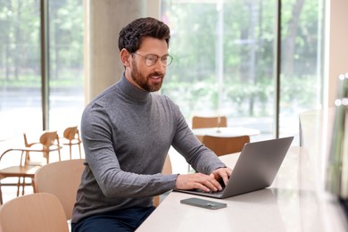 Photo of Man working on laptop at table in cafe