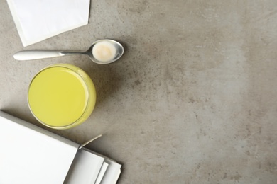 Photo of Medicine sachets, spoon and glass with dissolved drug on grey table, flat lay. Space for text