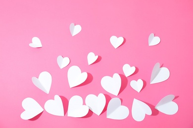 Small paper hearts on color background, top view