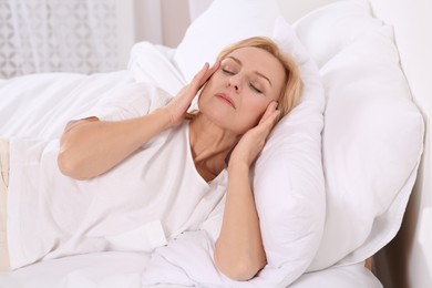 Photo of Woman suffering from headache in bed at home. Hormonal disorders