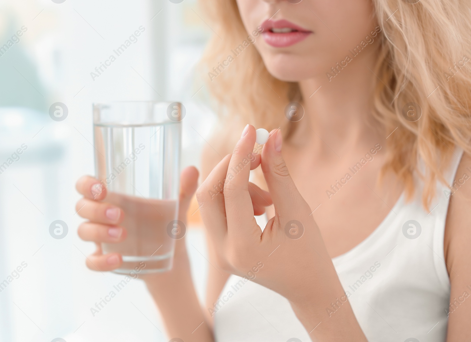 Photo of Young woman with pill and glass of water indoors