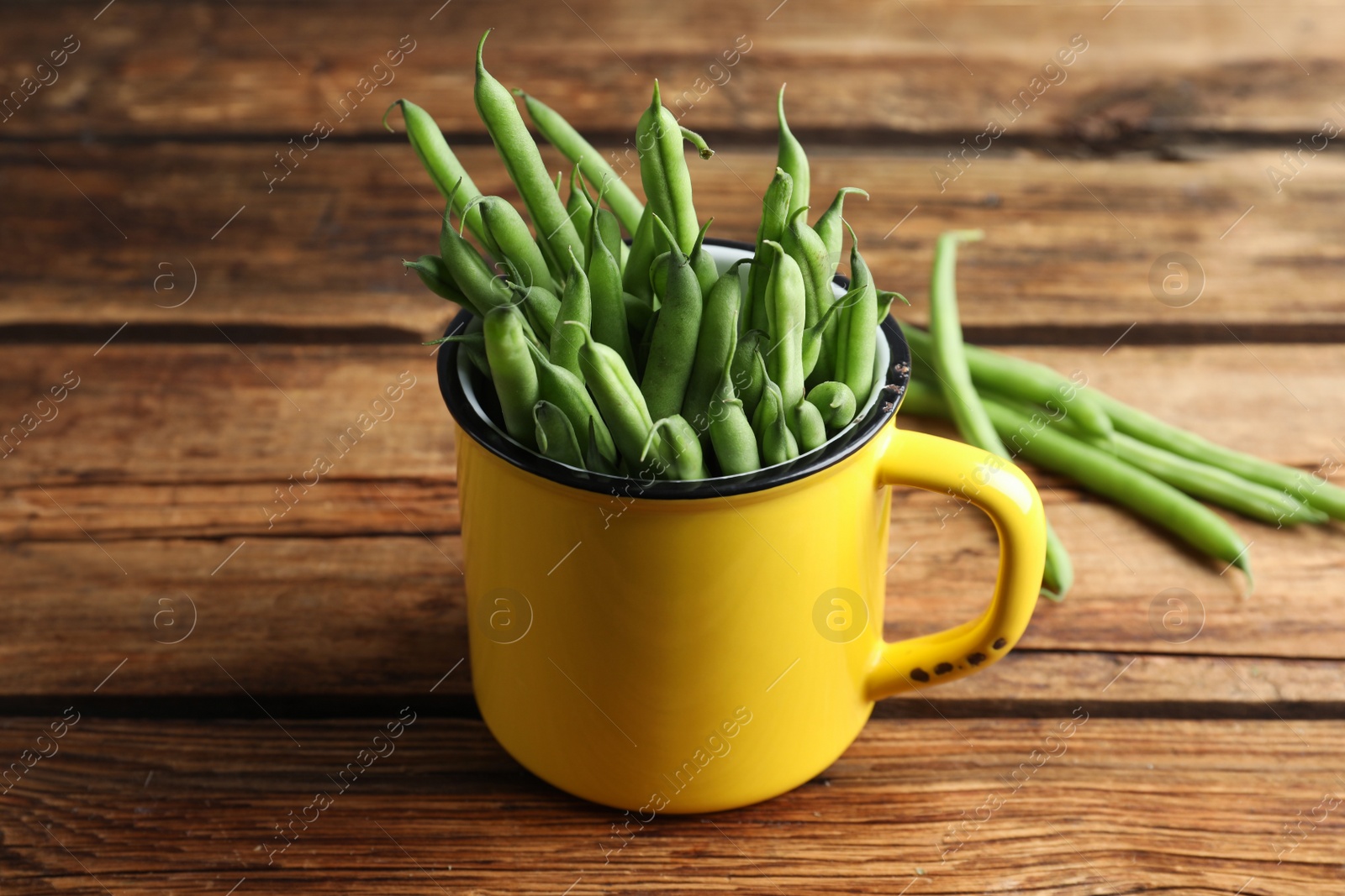 Photo of Fresh green beans in mug on wooden table