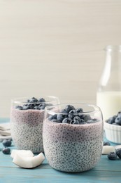 Delicious chia pudding with blueberries on light blue wooden table, space for text