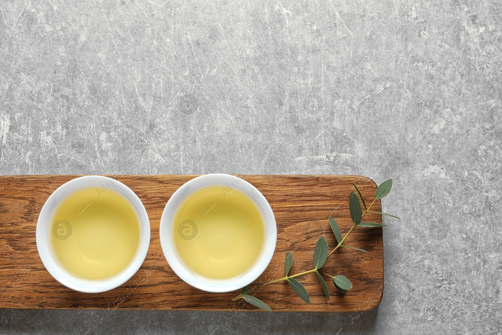 Photo of Stand with cups of freshly brewed oolong tea on grey background, top view with space for text