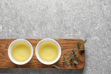 Stand with cups of freshly brewed oolong tea on grey background, top view with space for text