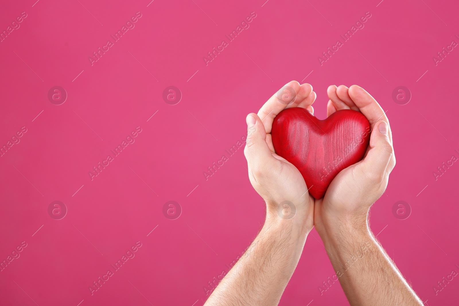 Photo of Man holding decorative heart in hands on color background, space for text