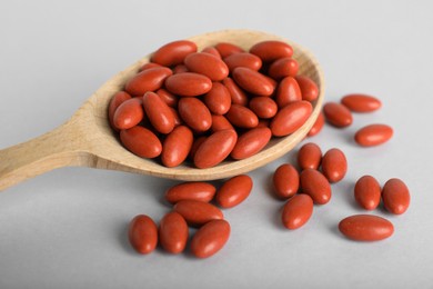 Photo of Wooden spoon with pills on light background, closeup. Anemia treatment
