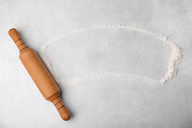 Photo of Rolling pin and flour on light grey table, top view. Space for text