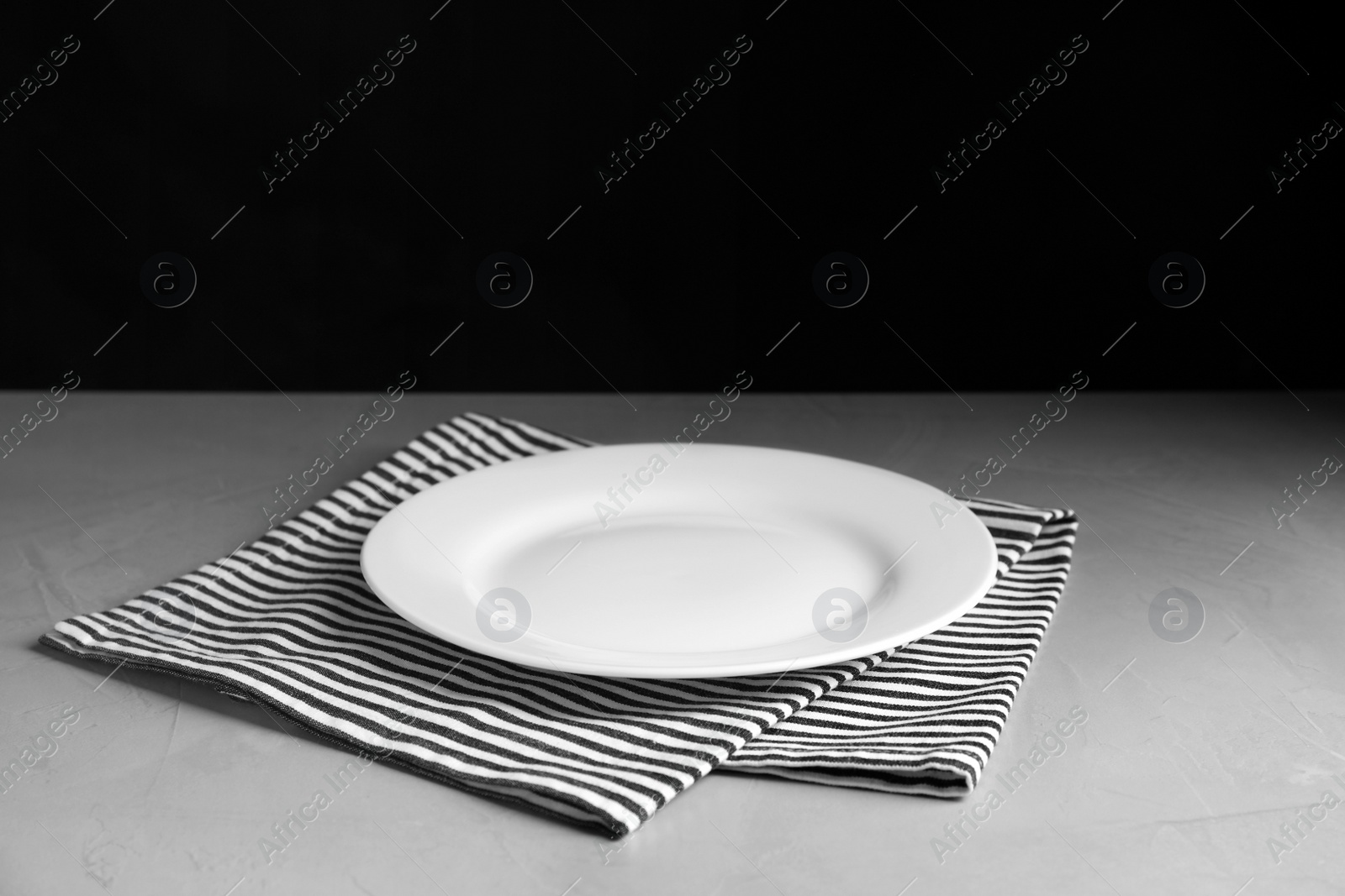 Photo of Empty ceramic plate and towel on light grey table