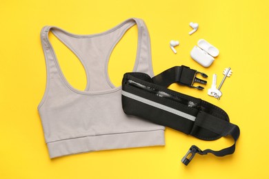 Flat lay composition with stylish black waist bag on yellow background