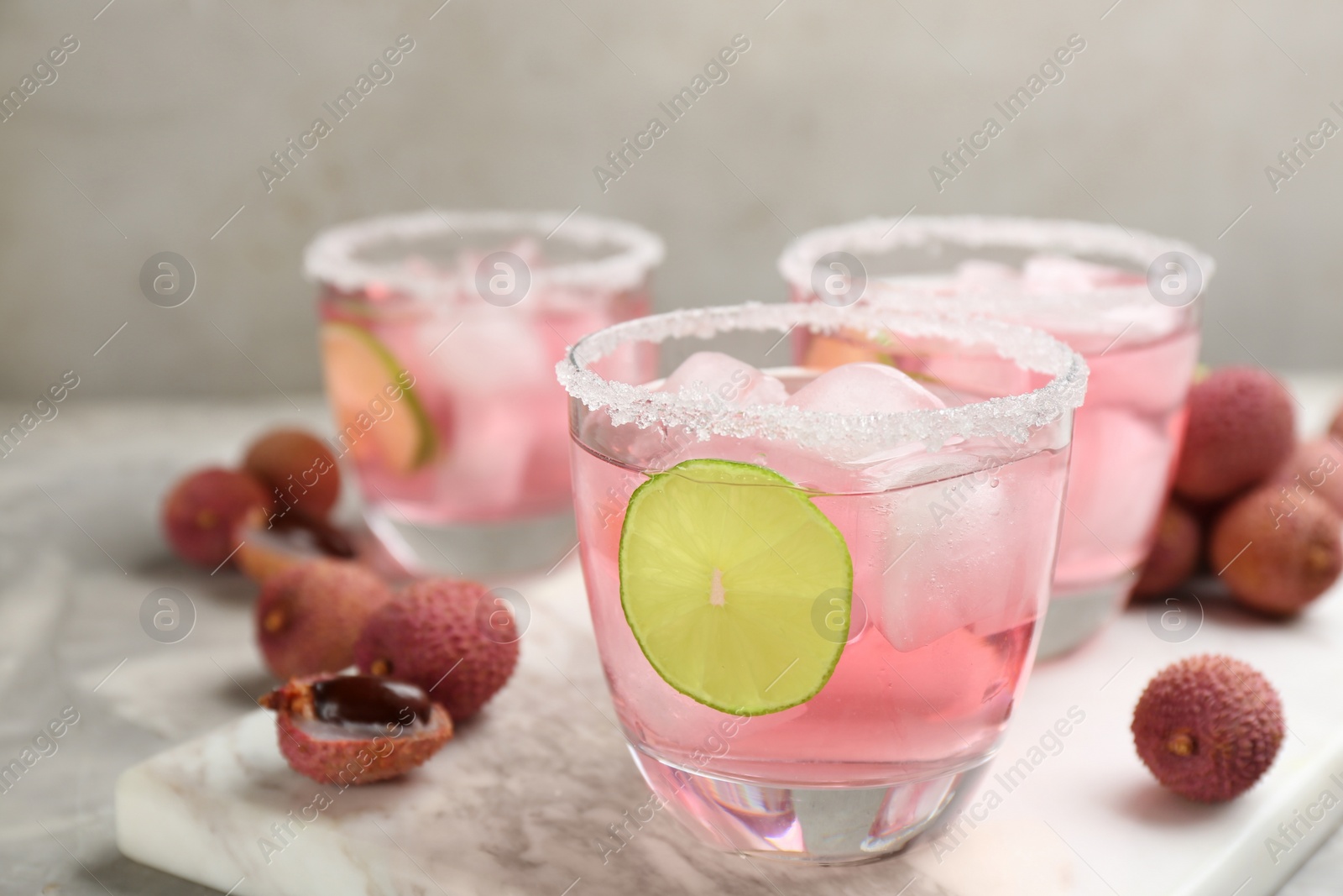 Photo of Lychee cocktail with lime and ice on grey table, closeup
