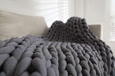 Photo of Soft chunky knit blanket on sofa in room, closeup