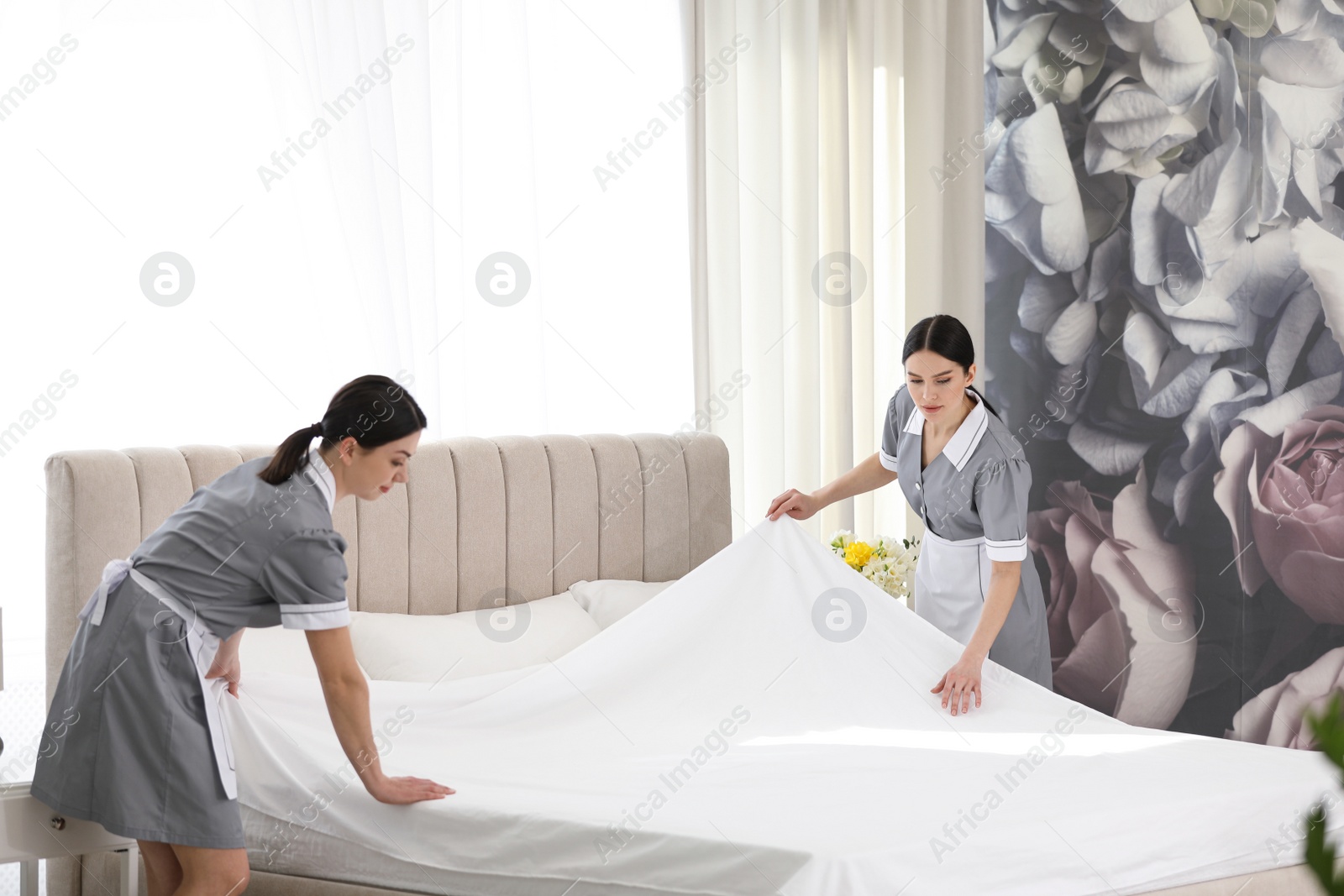 Photo of Young chambermaids making bed in hotel room