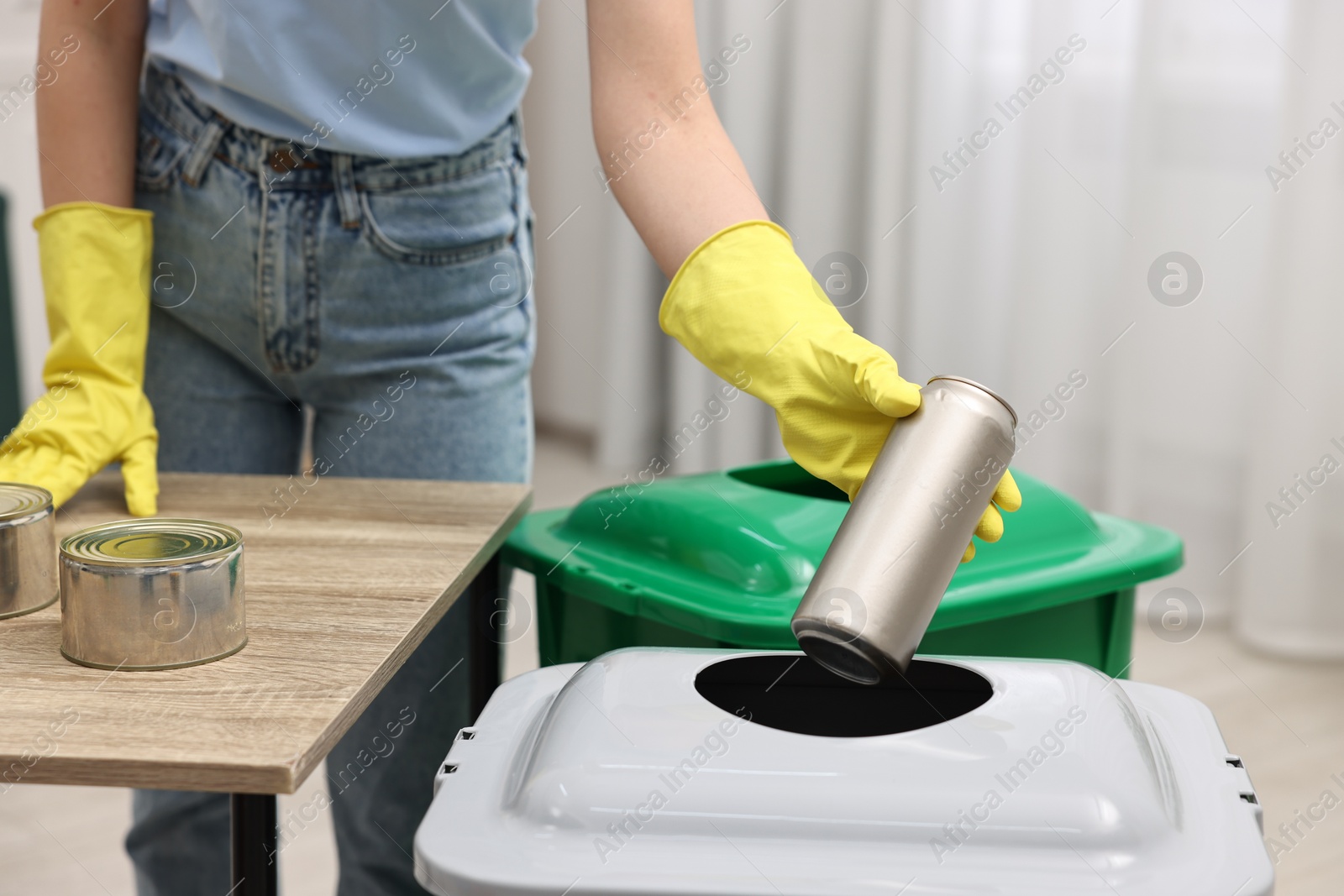 Photo of Garbage sorting. Woman throwing metal can into trash bin in room, closeup