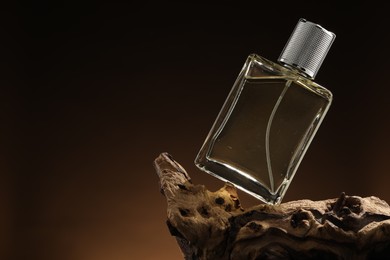 Photo of Luxury men`s perfume in bottle against brown background, space for text