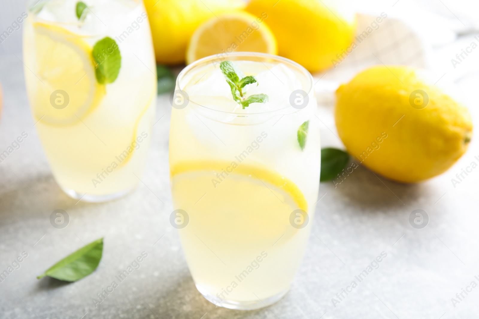 Photo of Glasses of cold lemonade on grey table, closeup